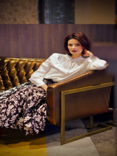 A lady wears shirt and floral skirt